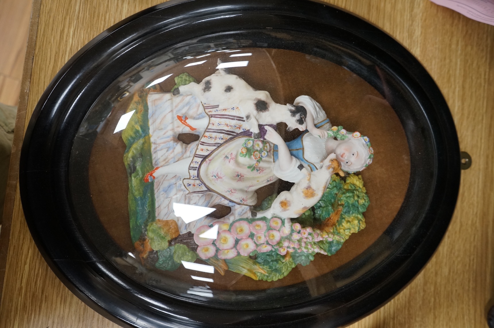 A pair of oval glazed biscuit porcelain plaques depicting figures, housed in ebonised frames, latter 43x34cm
